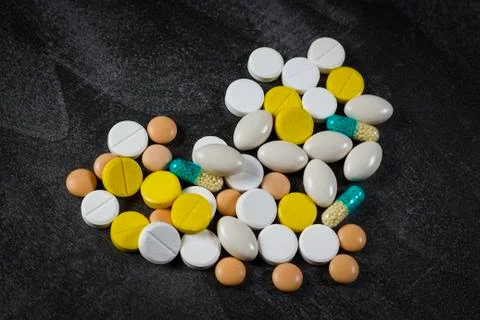 Heart made up of different tablets on a black table Stock Photos