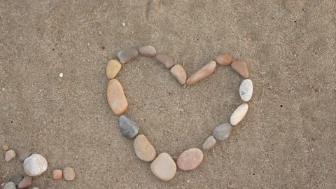 A heart made of rocks is on a sandy beach Stock Footage 276480930