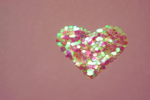 Heart made of sequins on a brown table. Copy space. 스톡 사진