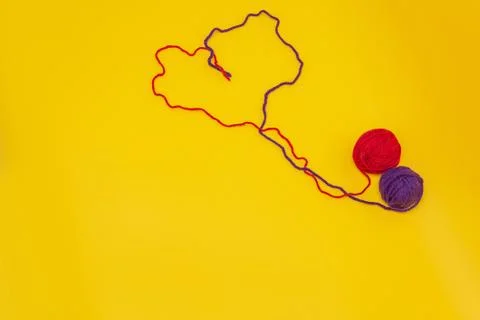 Heart of red and blue thread, unraveled from a tangle on an orange background Stock Photos