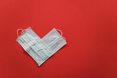 The heart on a red background is composed of two medical masks. Valentine's Day Stock Photos
