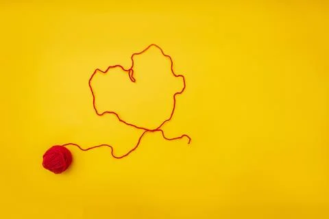 The heart of a red woolen thread from a ball is on a yellow background Stock Photos