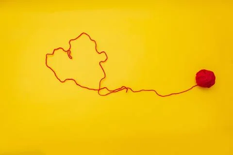 The heart of a red woolen thread from a ball is on a yellow background Stock Photos