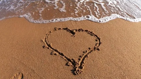 Heart in sand not affected by waves, strong love concept Stock Footage 111879176