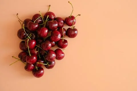 Heart shape cherries on peach background Stock Photos