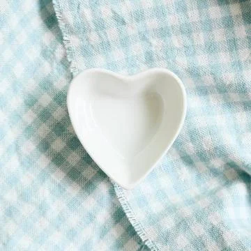 Heart shape dish on light blue check pattern cloth background Heart shape ... Stock Photos