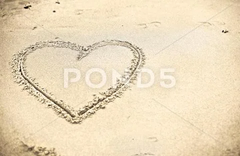 Heart shape drawn on sand Stock Photos