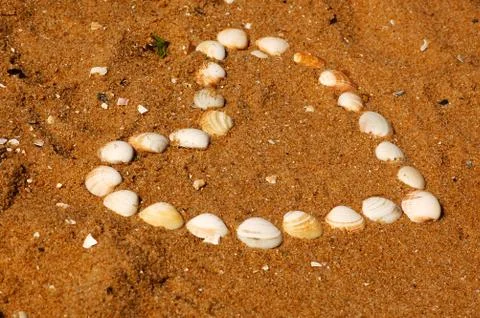 Heart shape drawn in the sand with shells. Love bay. Stock Photos