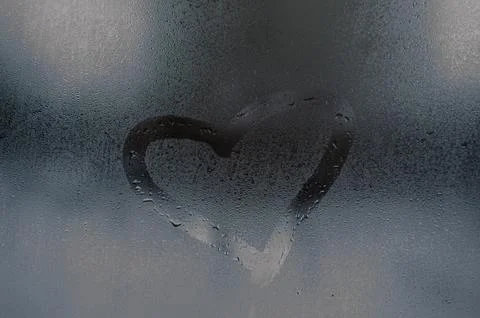 Heart Shape Drawn on Steamy Window Glass with Water Droplets Foto stock