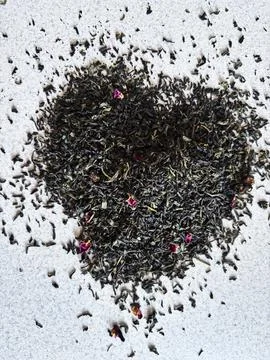 A heart shape formed by loose leaf tea rests on a light textured surface, com 写真素材