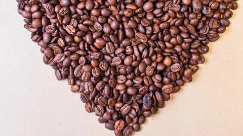 Heart shape formed by roasted coffee beans on a light background Stock Photos