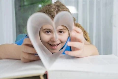 Heart shape frames child face. Heart symbol from book pages. Heart shows love 库存照片