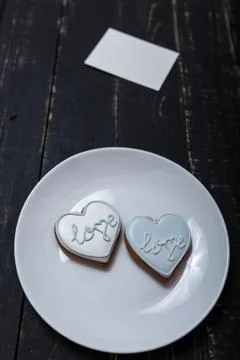 Heart shape gingerbread cookie on white plate standing on black wooden table Stock-Fotos