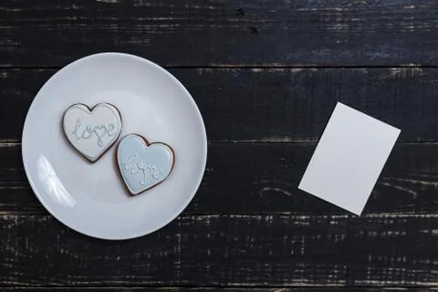 Heart shape gingerbread cookie on white plate standing on black wooden table Stock Photos