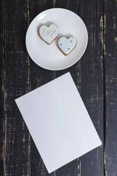 Heart shape gingerbread cookie on white plate standing on black wooden table Stock Photos