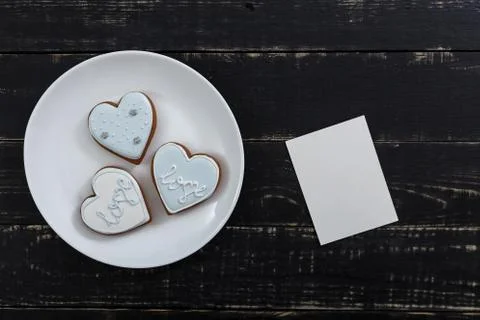 Heart shape gingerbread cookie on white plate standing on black wooden table Foto stock