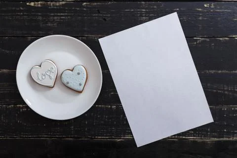 Heart shape gingerbread cookie on white plate standing on black wooden table Stock-Fotos