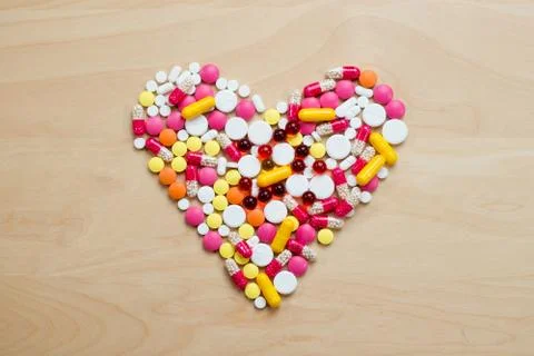 Heart shape laid out of multi-colored pills Stock Photos