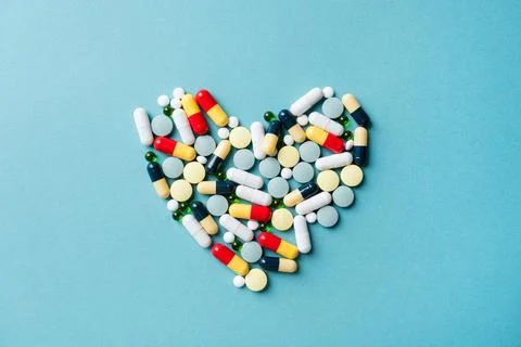 Heart shape made of different pills on blue background Stock Photos