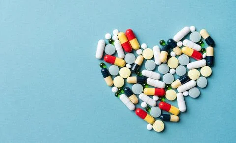 Heart shape made of different pills on blue background Stock Photos