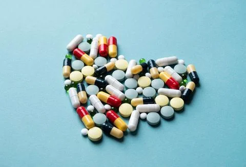 Heart shape made of different pills on blue background Stock Photos