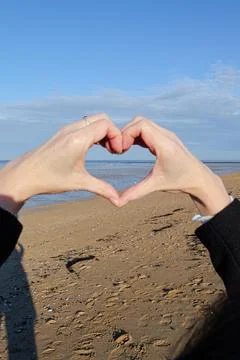 Heart shape made with hands on sandy beach, love and romance concept Stock Photos