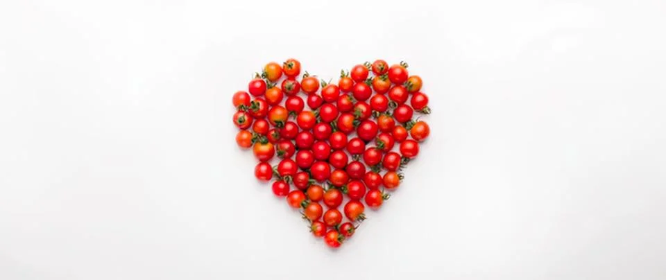 Heart shape made of red cherry tomatoes on white background Stock Photos