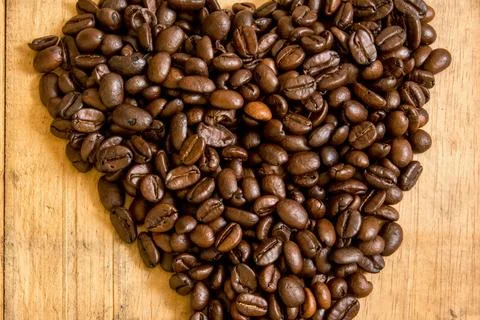 Heart shape made of roasted coffee beans on a wooden surface Stock Photos