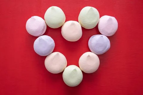 Heart shape from multi-colored pastel marshmallows on a red wooden background Stock Photos