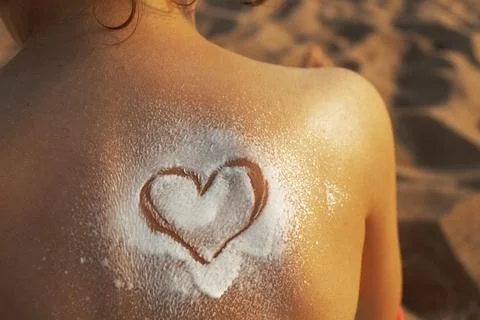 Heart shape painted on the baby's back with sunscreen on beach Stock Photos