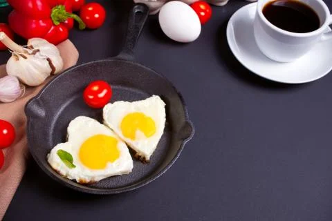 Heart shape scrambled eggs on iron dark pan Stock Photos
