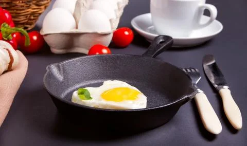 Heart shape scrambled eggs on iron dark pan 库存照片