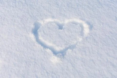 A heart shape squeezed into the white snow. The basis for the postcard. Place Foto stock