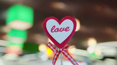Heart-shaped attribute on a stick against the blurred background, multi-colored Stock Footage 170012308