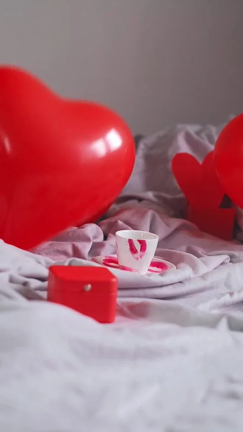 Heart-shaped balloons fall on the bed, concept of a festive breakfast in bed for Stock Footage 298184569