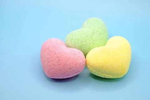Heart-shaped bath bombs in close-up on a blue background Stock Photos