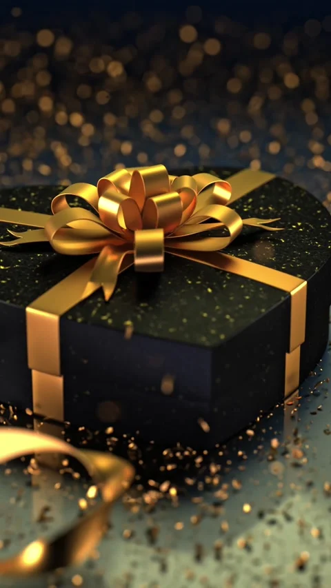 A heart-shaped black box with a shimmering gold bow and glittering dots sit.. Stock Footage 295346290