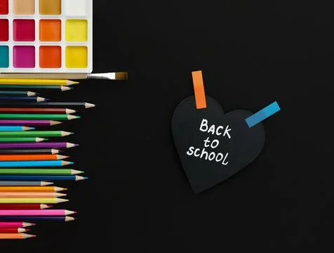 Heart shaped board with back to school inscription colored pencils and Stock Photos