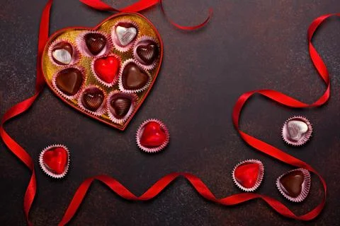 Heart-Shaped Box of Assorted Chocolates with Red Ribbons on Rustic Background Stock Photos