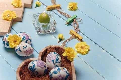 Heart shaped box with decorated Easter eggs, yellow flowers, burning candle Stock Photos