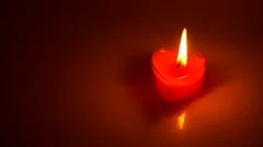 Burning heart shaped candle over red background, Stock image