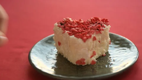 A heart-shaped cake is placed on a red tablecloth Stock Footage 147035710