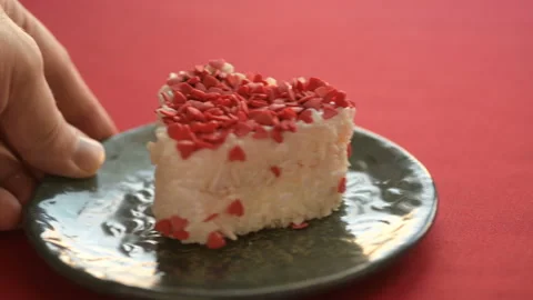 A heart-shaped cake is placed on a red tablecloth Stock Footage 147036028