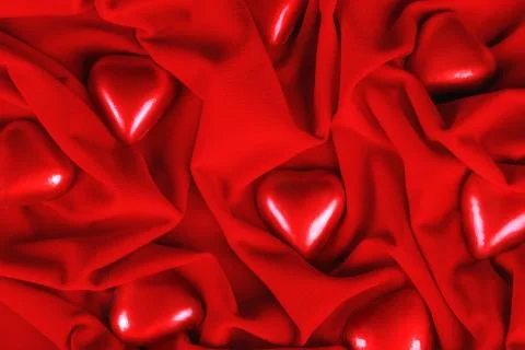 Heart shaped chocolate sweets in red foil on red cloth. Stock Photos