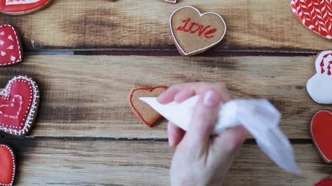 Heart shaped cookies decorating process with pink cream. Closeup of female hand Stock-Footage 119027233