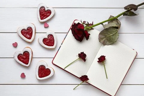 Heart shaped cookies with empty notebook and roses on white wooden background Stock Photos