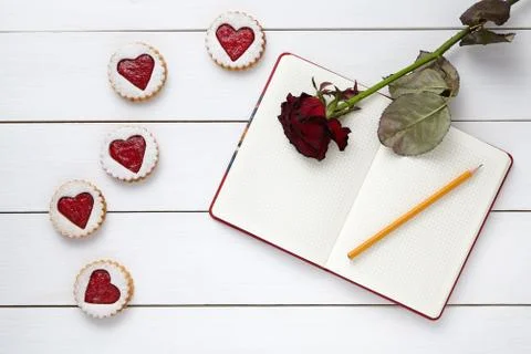 Heart shaped cookies with empty notebook, pencil and rose flower on white wooden Stock Photos