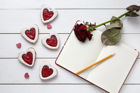 Heart shaped cookies with empty notebook, pencil and red rose gift on white Stock Photos