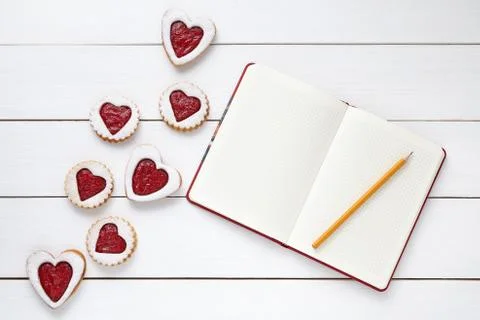 Heart shaped cookies with empty notebookand pencil on white wooden background Stock Photos