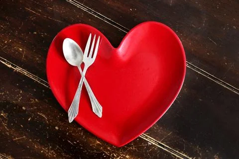 Heart Shaped Dinner Plate with Fork and Spoon on Worn Wood Table Stock Photos